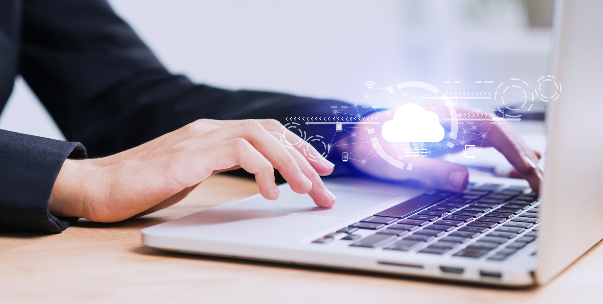 primo piano di mani posate sulla tastiera di un pc con icone di nuvole rappresentative del cloud